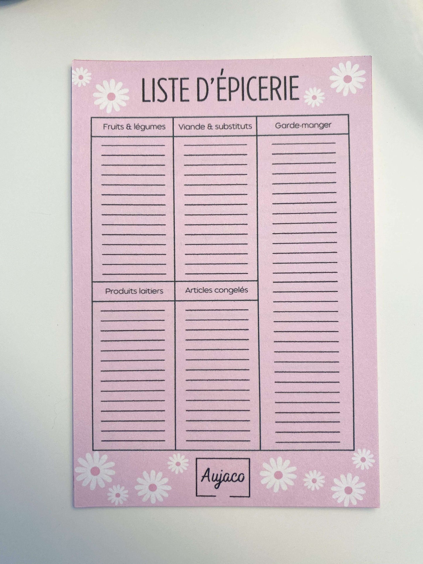 alt="Liste d'épicerie au format 4x6 pouces, design simple sur fond rose avec marguerites blanches, sections pour fruits et légumes, viande et substituts, garde-manger, produits laitiers et articles congelés, plusieurs lignes spacieuses, 40 pages, papier cartonné épais pour une durabilité supérieure."