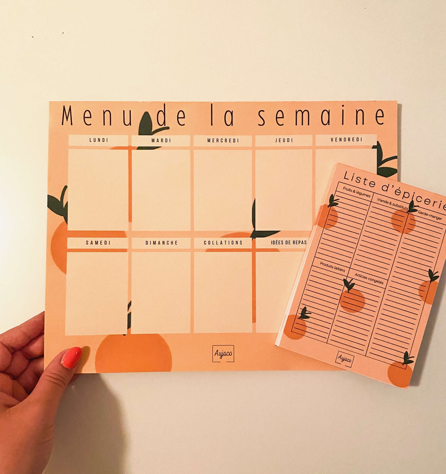 alt="Planificateur de repas hebdomadaire Citrons et Cerises de couleur orange avec petites oranges en arrière-plan, sections dédiées pour chaque jour et collations, espace pour noter idées de repas et articles à acheter, format compact 8.5 x 11 pouces, 40 pages, option aimants, design moderne et durable de Aujaco."