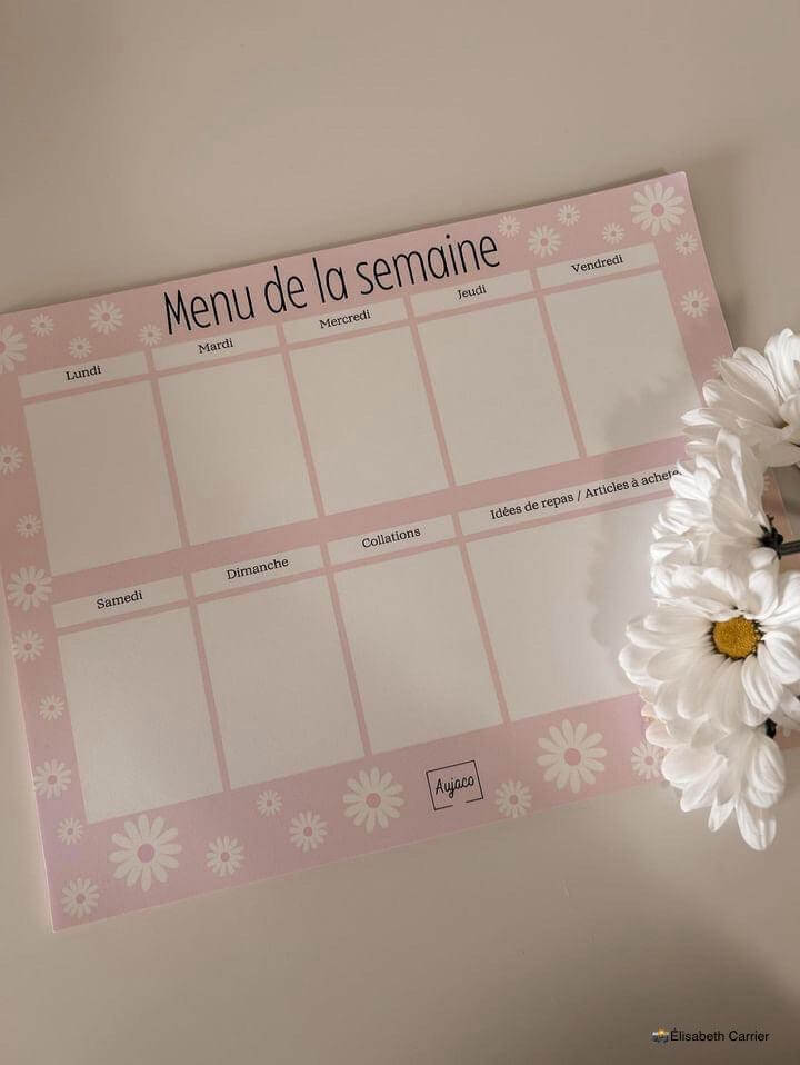 alt="Planificateur de repas hebdomadaire Pink Era avec des marguerites blanches, design simple et féminin de couleur rose, sections dédiées pour chaque jour et collations, grand espace pour noter idées de repas et articles à acheter, format compact 8.5 x 11 pouces, 40 pages, option aimants, papier cartonné épais pour une durabilité supérieure."