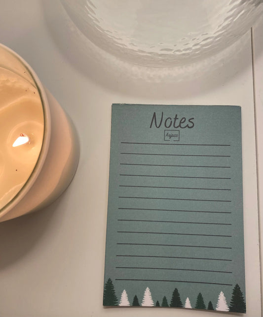 alt="Bloc-notes de style carnet par Aujaco, design simple et hivernal avec sapins blancs et verts sur fond vert. Dimensions 4 x 6 pouces, plusieurs lignes pour notes, papier cartonné épais, 40 pages."