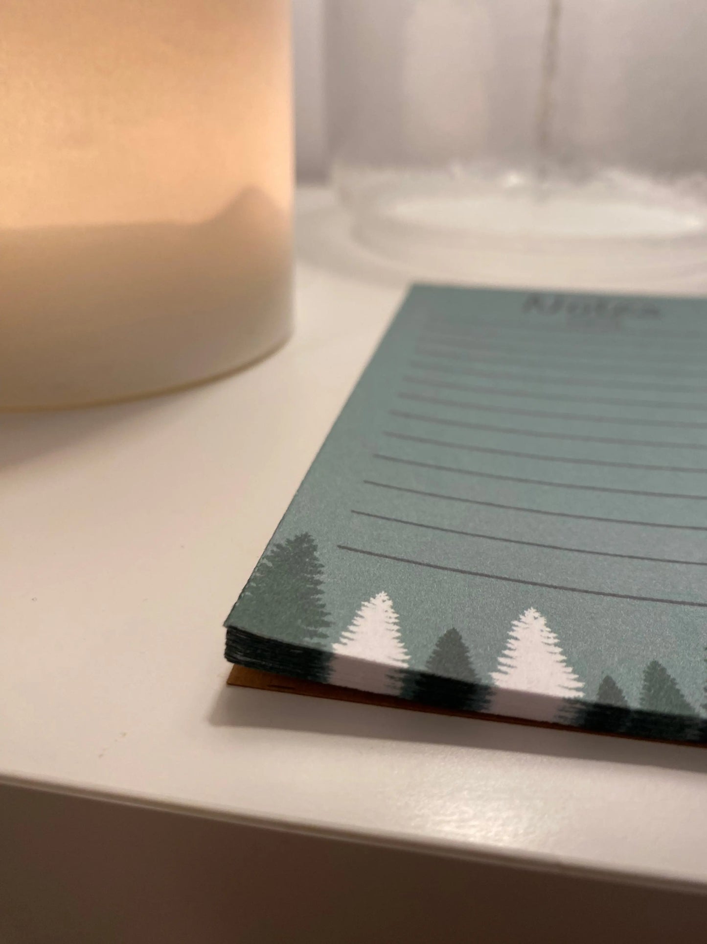 alt="Bloc-notes de style carnet par Aujaco, design simple et hivernal avec sapins blancs et verts sur fond vert. Dimensions 4 x 6 pouces, plusieurs lignes pour notes, papier cartonné épais, 40 pages."