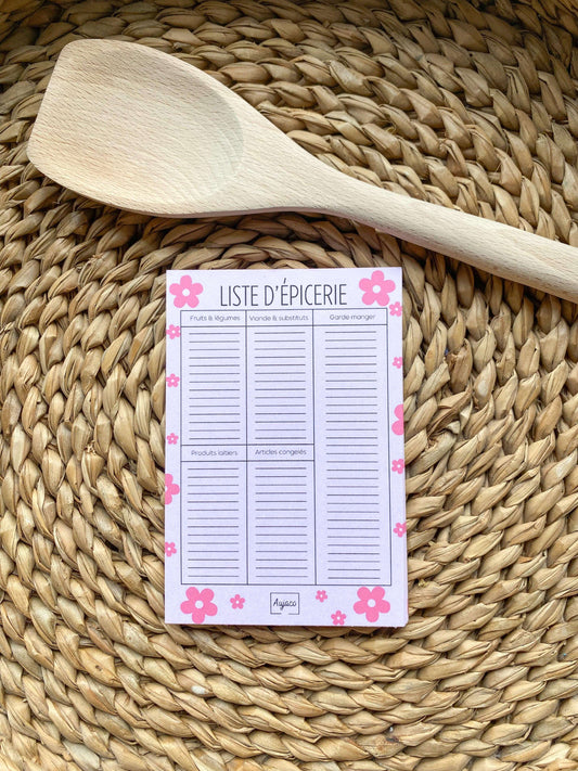 alt="Liste d'épicerie au format 4x6 pouces, design simple sur fond rose avec fleurs roses, sections pour fruits et légumes, viande et substituts, garde-manger, produits laitiers et articles congelés, plusieurs lignes spacieuses, 40 pages, papier cartonné épais pour une durabilité supérieure."
