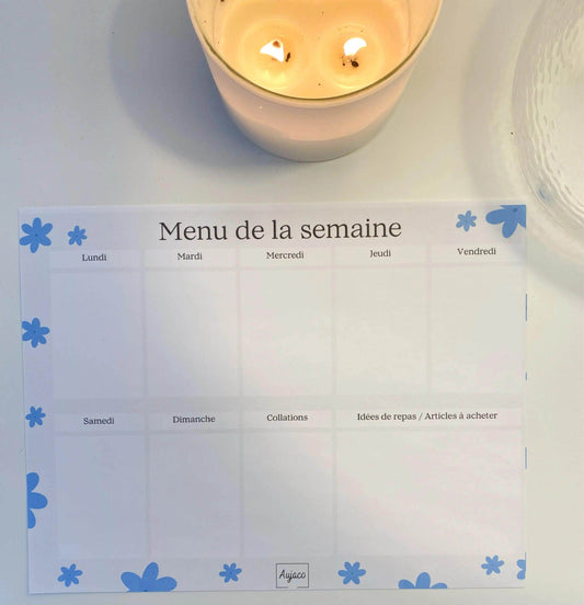alt="Planificateur de repas hebdomadaire Fleurs bleues avec fleurs blanches délicates, sections dédiées pour chaque jour et collations, espace pour noter idées de repas et articles à acheter, format compact 8.5 x 11 pouces, 40 pages, option aimants, design moderne et durable."
