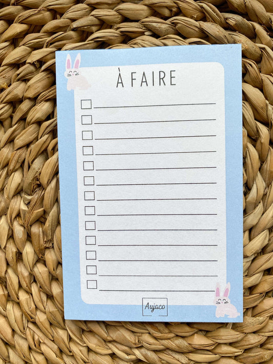 alt="To-do list avec design simple et deux lapins sur fond bleu, format compact 4 x 6 pouces, plusieurs cases à cocher pour les tâches, papier cartonné épais pour une meilleure durabilité, 40 pages."
