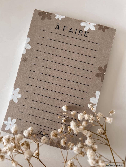 alt="To-do list 4x6 pouces par Aujaco, design simple avec fleurs blanches et beiges sur fond beige chaud. Format compact avec plusieurs cases à cocher. Papier cartonné épais avec 40 pages."